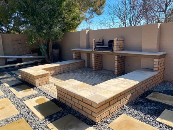 Close-up of a built-in brick braai and seating structure in the corner of the courtyard.