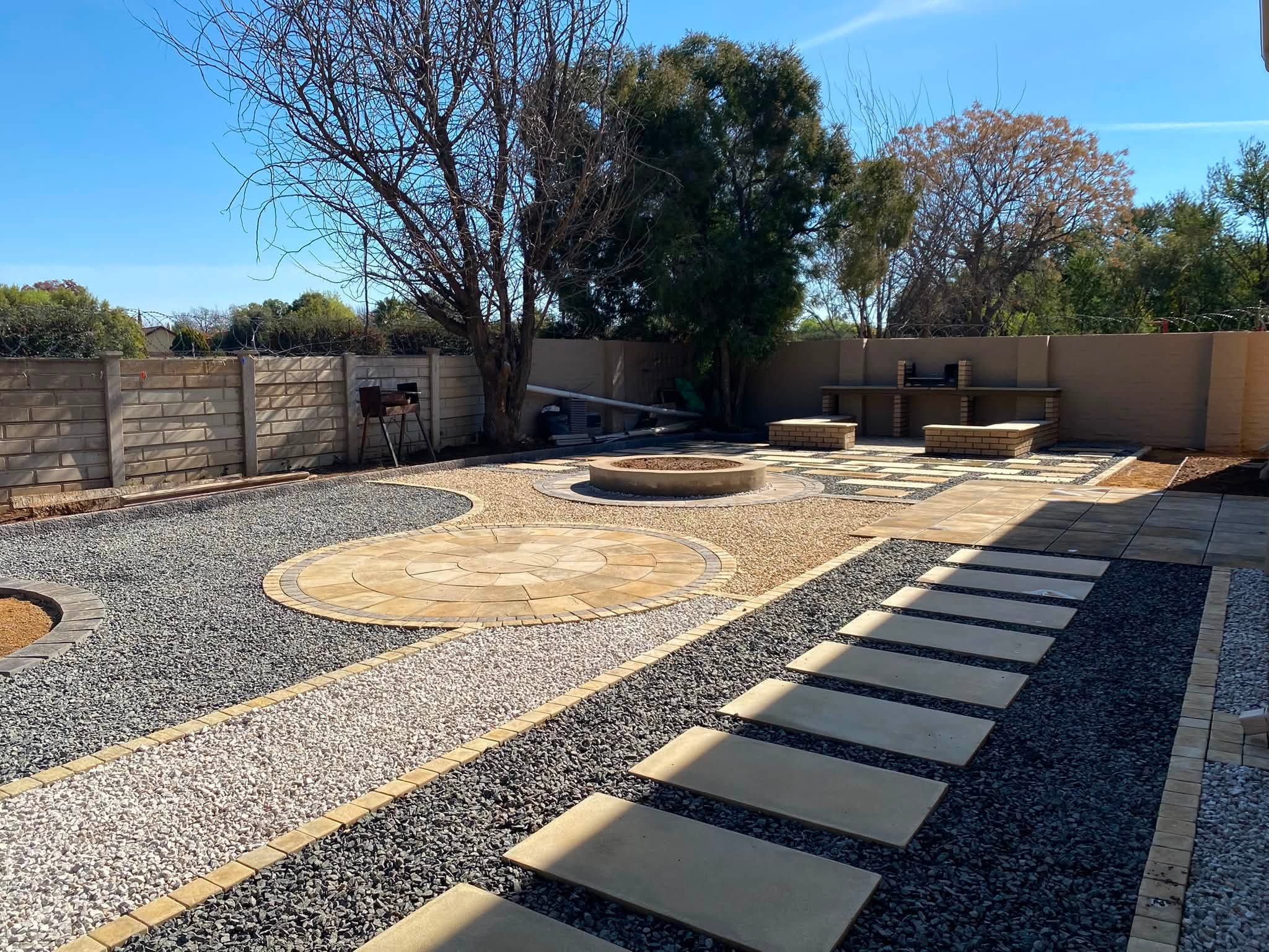 Completed paved boma and fire-pit courtyard with built-in seating, circular paving and gravel landscaping, Bloemfontein.