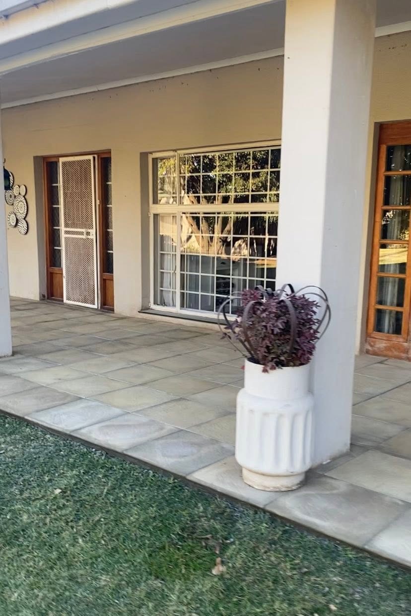 Covered patio with large sandstone-look paving under a home's veranda.