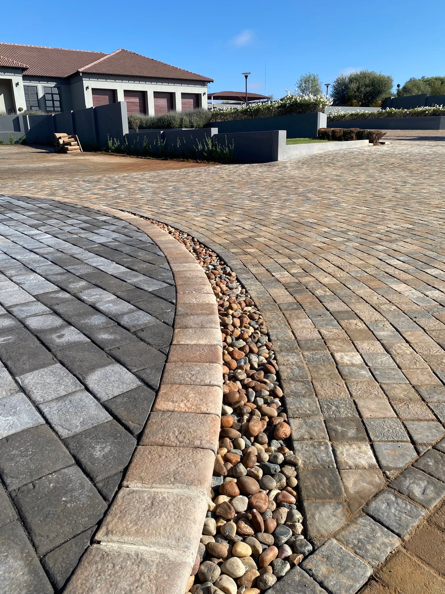 Curved paving edge with a river-pebble drainage border, detail shot.